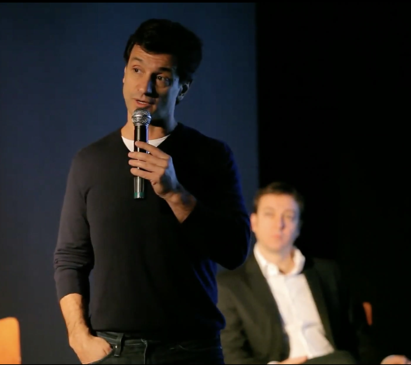 A speaker on the Journée du Luxe stage, another guest seated behind him